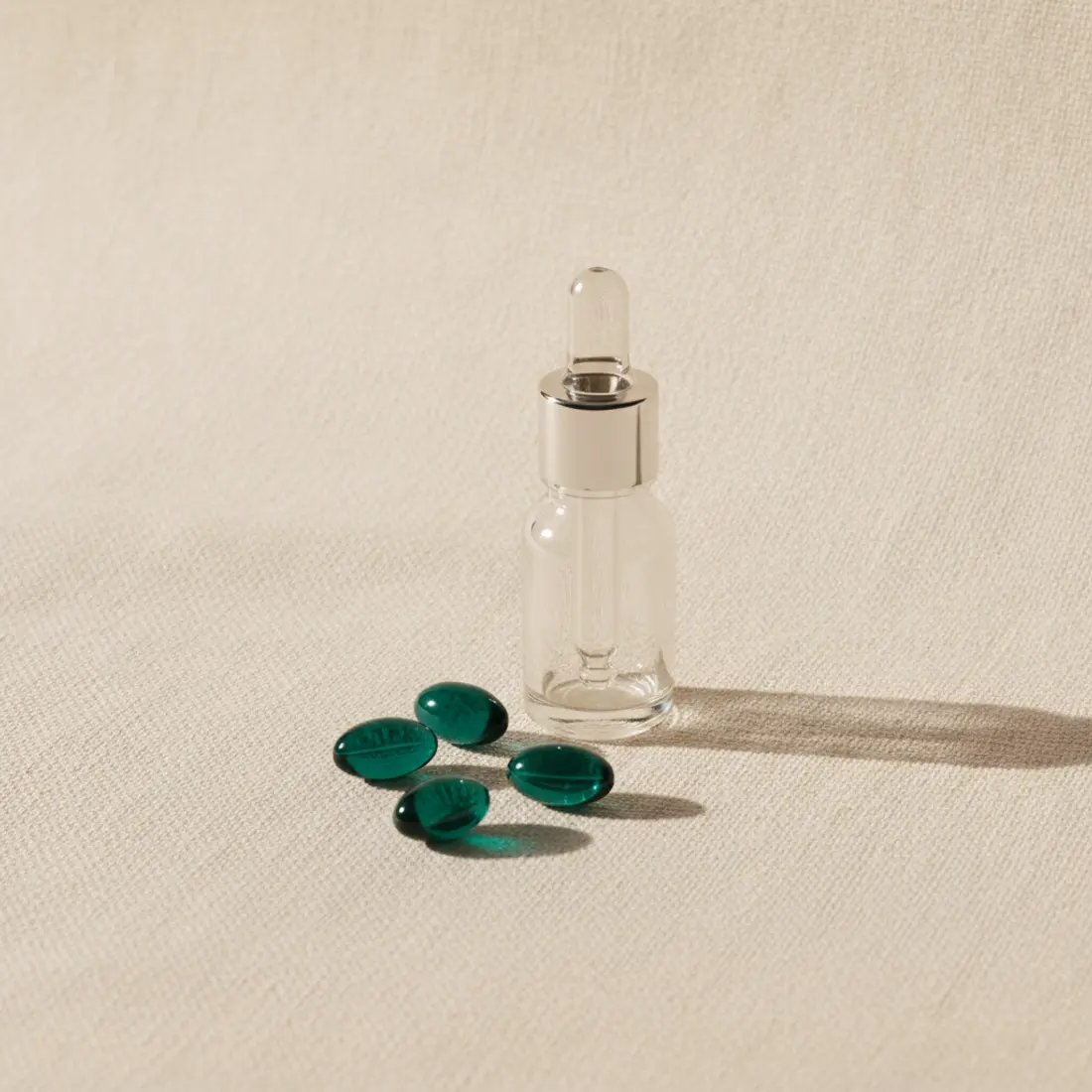 Collagen capsules and a serum dropper on linen